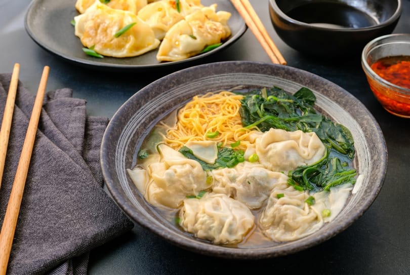 Wonton noodle soup with spinach and a side of pan-fried dumplings and chili oil.